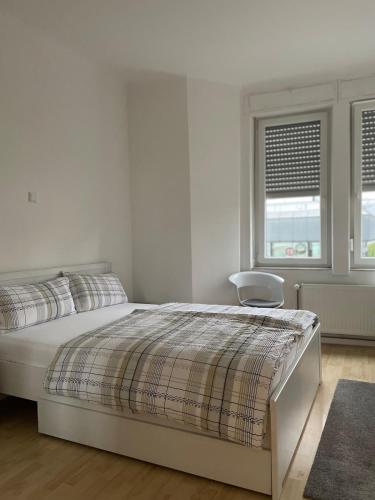 a white bedroom with a bed and a chair at Wohnung Karl-Marx 1 in Trier