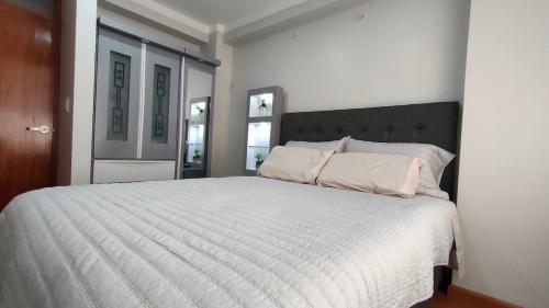 a bedroom with a large white bed with two pillows at Apartamento Flores in Puno