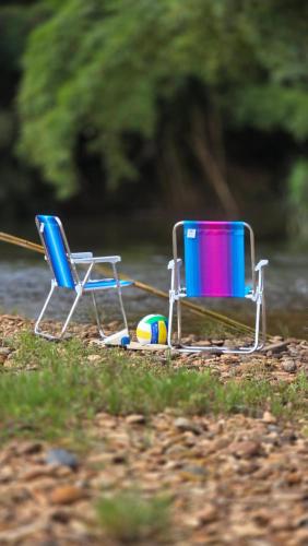two chairs and a ball on a beach at Beira Rio Casa Canastra in Vargem Bonita