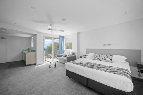 a white bedroom with a bed and a couch at The Dorsal Boutique Hotel in Forster