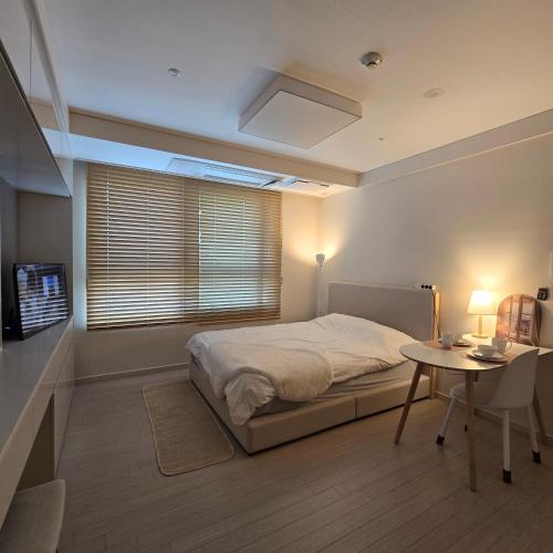 a bedroom with a bed and a table and a window at 원 스테이 광명역 in Gwangmyeong