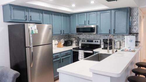 a kitchen with blue cabinets and a stainless steel refrigerator at Walkable Location - 99 Steps to Beach - Pool apts in South Padre Island
