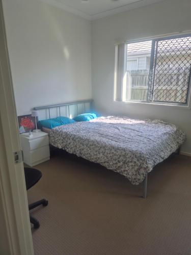 a bedroom with a bed with blue pillows and a window at One Bedroom One Bathroom Unit With a New TV in Wulkuraka