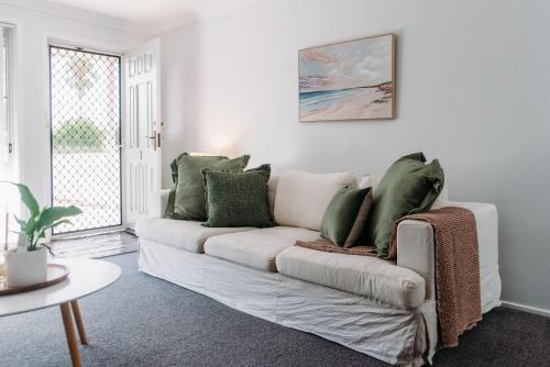 a living room with a white couch with green pillows at The Retreat on Piper in Tamworth
