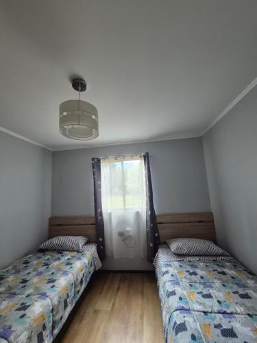 a bedroom with two beds and a window at Cabaña arenal in Pucón