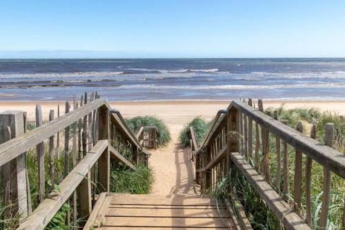 a wooden staircase leading to a beach with the ocean at The Beach House in Mablethorpe