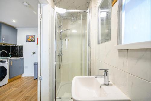 a white bathroom with a shower and a sink at Phenomenal Stay - Private Parking & Hot tub in Liversedge