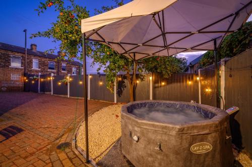 a hot tub with an umbrella in a yard at Phenomenal Stay - Private Parking & Hot tub in Liversedge