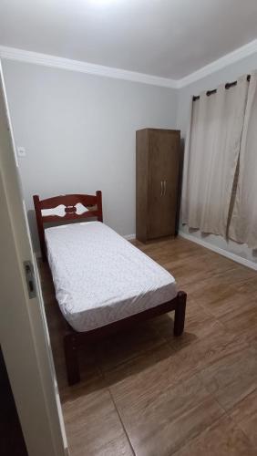 a small bedroom with a bed and a cabinet at Casa inteira, Nações in Patrocínio