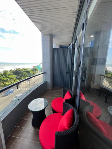a balcony with red chairs and a table and the beach at Tuyết Nhi in Vung Tau