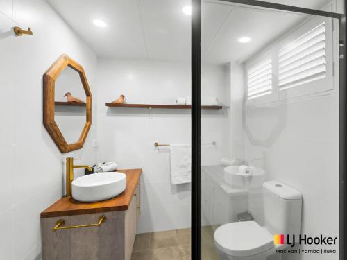 a bathroom with a sink and a toilet and a mirror at Iluka Villa 2 in Iluka