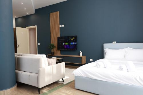 a bedroom with two white chairs and a bed and a tv at Palm Vista Retreat in Durrës