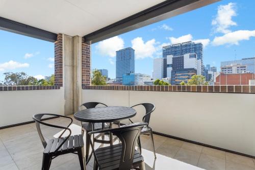 a balcony with a table and chairs and a view of the city at The Cullinan Apartments by CLLIX in Adelaide