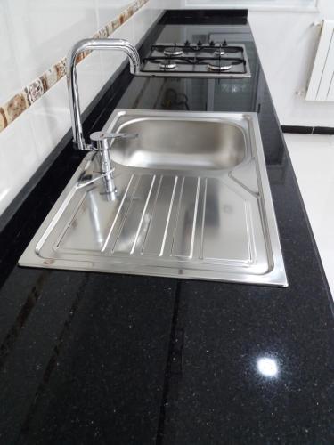 Un fregadero de acero inoxidable en una cocina junto a una estufa. en Moderne Appart Tlemcen, en Tlemcen