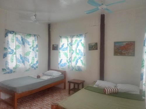 a room with two beds and a ceiling fan at Enas Cottage Pamilacan IsLand in Baclayon