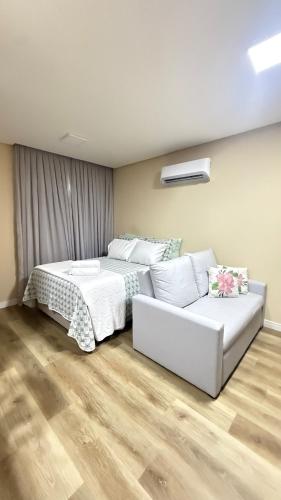 a bedroom with a white bed and a couch at Studio no centro de Pomerode! in Pomerode