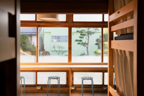 a room with a window and two stools at Guest House hopin in Nagano