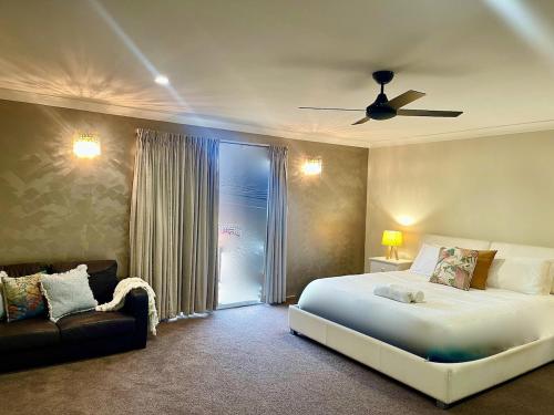 a bedroom with a large bed and a couch at Lahool Cottage in Stanthorpe