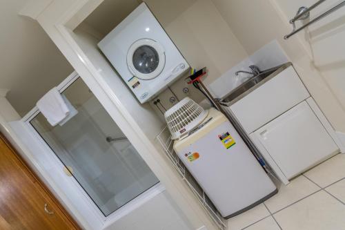 a small kitchen with a refrigerator and a washing machine at Southern Cross Atrium Apartments in Cairns