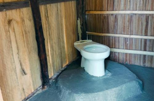 a bathroom with a toilet in a wooden stall at War Homestay in Pulau Minyaifuin
