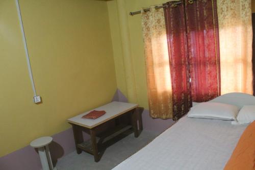 a small bedroom with a bed and a table at Shanta Ghar A Rustic Guesthouse in Chitwan