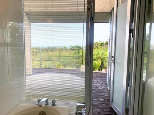 a bathroom with a window with a view of a yard at Private Villa The Beach AMAMI in Tatsugo