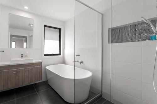 a white bathroom with a tub and a sink at The Lavender House in Gledswood Hills