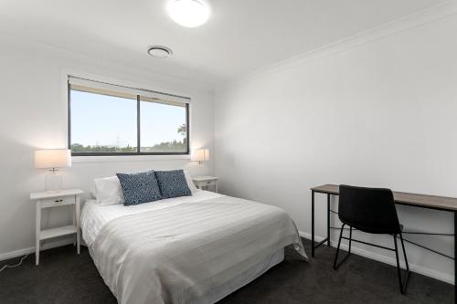 a bedroom with a bed and a desk and a window at The Lavender House in Gledswood Hills