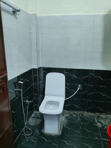 a bathroom with a white toilet in a black tiled wall at Hotel vivekanand in Badrinath