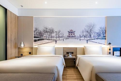 two beds in a room with a painting on the wall at Atour Hotel Jining High-tech Zone in Jining