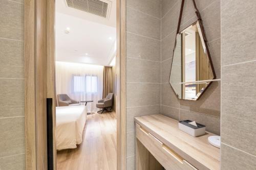 a room with a bed and a mirror and a bathroom at Atour Hotel Jining High-tech Zone in Jining