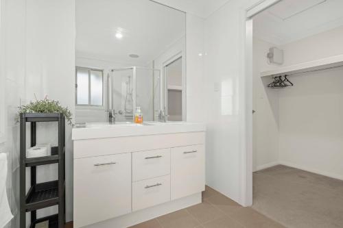 a white bathroom with a sink and a mirror at Manning the Waves in Kiama
