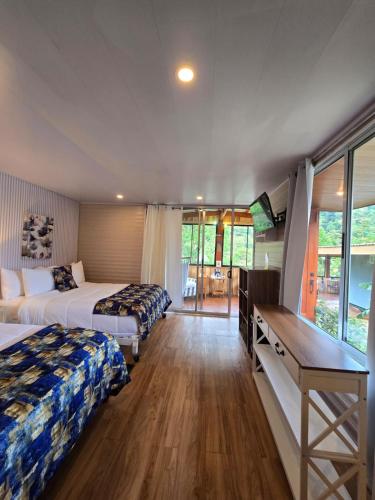 a bedroom with two beds and a desk and a table at Blue Morpho Lodge & Spa in Bajos del Toro