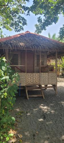 a hut with a straw roof on top of it at Mananambal Beach Huts - Hut 2 in Nagbalaye