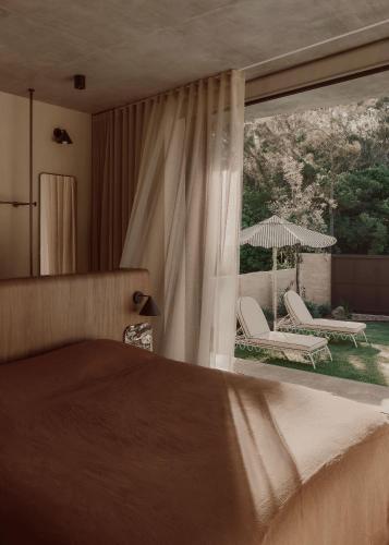 una camera da letto con un letto e due sedie e una grande finestra di Arrawarra Beach House ad Arrawarra