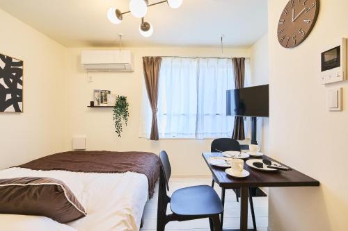 a bedroom with a bed and a table and a clock at Reberty Haneda in Tokyo