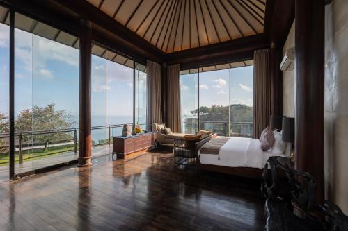 a bedroom with a bed and a view of the ocean at By The Cliff Bali Villa in Jimbaran