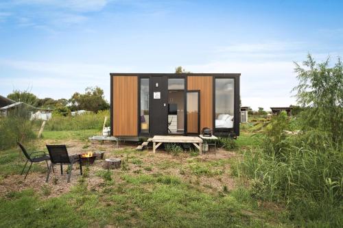 a tiny house in a field with a table and chairs at Revillaging Project by Tiny Away in Boneo