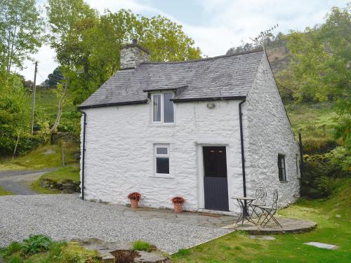 a white cottage with a black roof on a hill at Crogen Bryn Awel in Llandrillo
