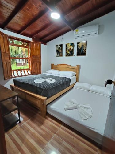 a bedroom with two beds and a window at Hotel Campestre la Meseta in Puerto Boyacá
