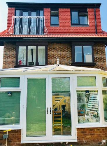 a house with large sliding glass doors in front of it at Read Oak Lodge - Spring Offer - Free Parking - Kitchen Laundry Facility - Near PRUH - Orpington - 20 Mins from London Bridge in Farnborough