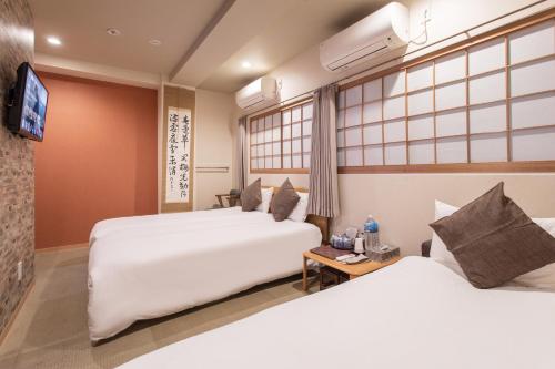 a hotel room with two beds and a tv at Saikou in Osaka