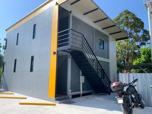 a motorcycle parked in front of a building with a staircase at ท่าเรือห้องพัก Tha Ruea hongpak in Ban Na Sat