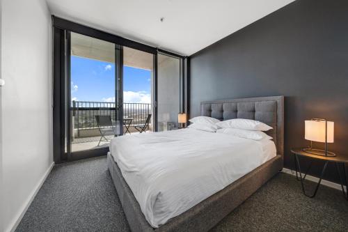 a bedroom with a large bed and a large window at Chic 1-Bed with Stunning Lake View & Indoor Pool in Belconnen
