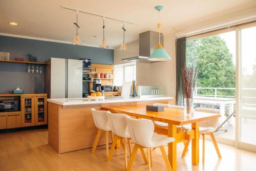 a kitchen with a wooden table and white chairs at chillout house 大室山 in Ito