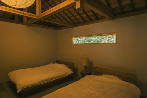 a bedroom with two beds and a window in it at 比地の宿 in Kunigami