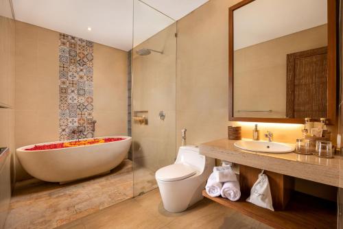 a bathroom with a tub and a toilet and a sink at Kahayana Suites Ubud in Ubud