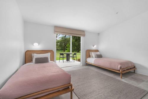 two beds in a room with a table and a window at Grovebrook Cottage, Broughton in Woodhill