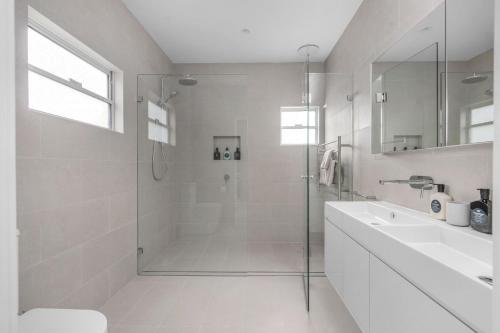 a white bathroom with a shower and a sink at Grovebrook Cottage, Broughton in Woodhill