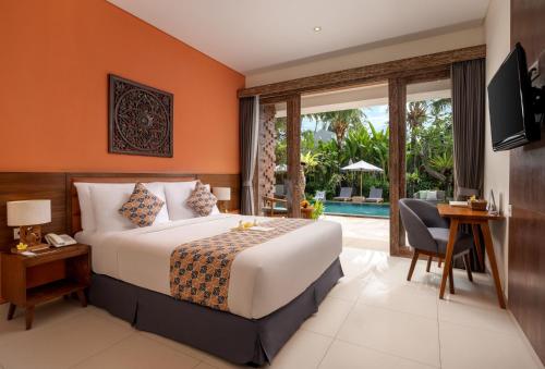 a bedroom with a bed and a desk and a television at Kahayana Suites Ubud in Ubud